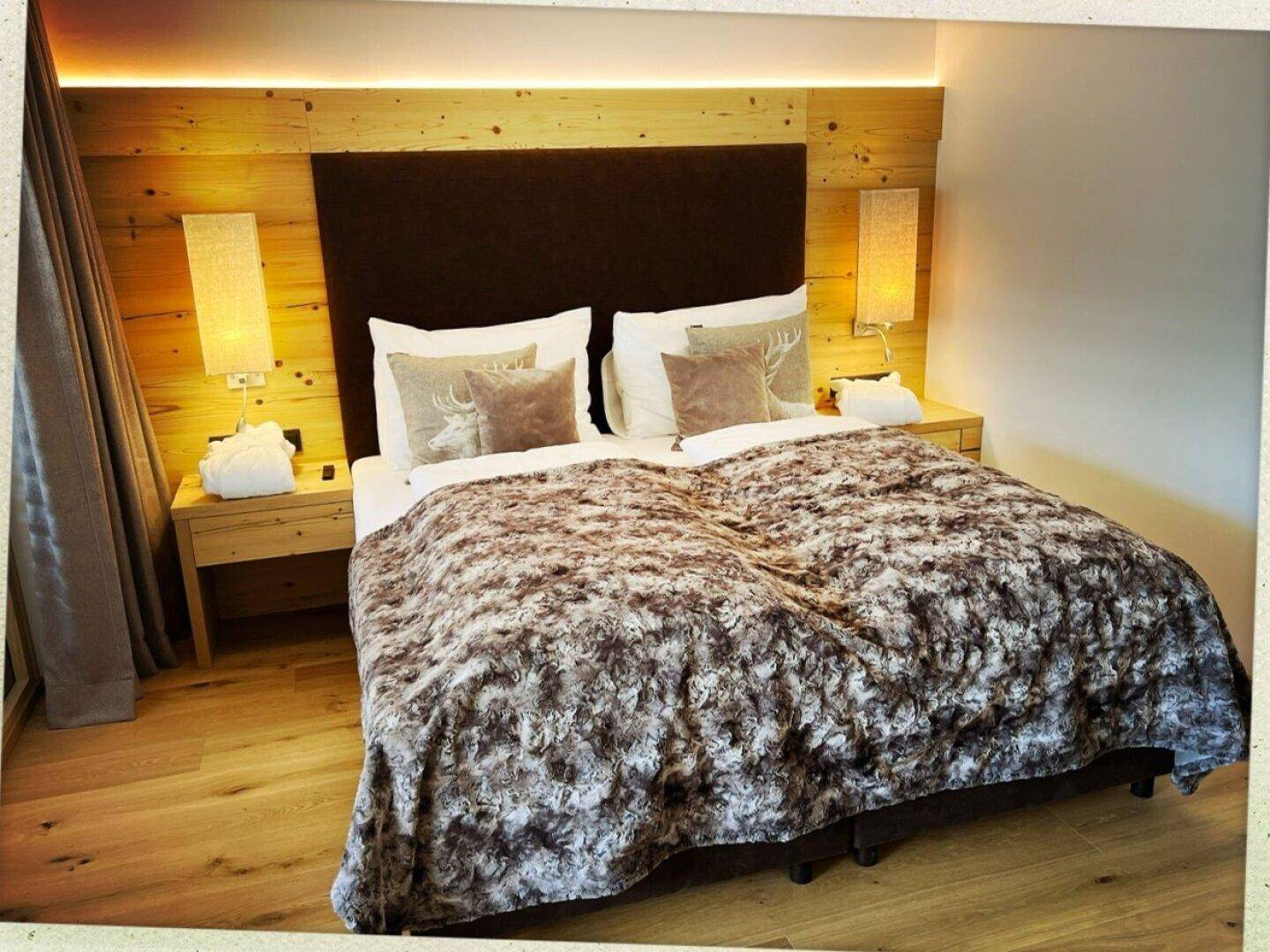 Gemütliches Schlafzimmer mit Holzakzenten, großem Bett und alpiner Dekoration.