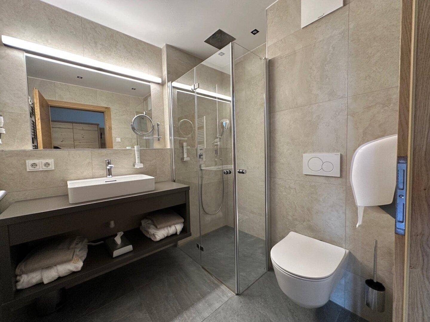 Modernes Badezimmer mit begehbarer Dusche, Wand-WC und großem Spiegel.