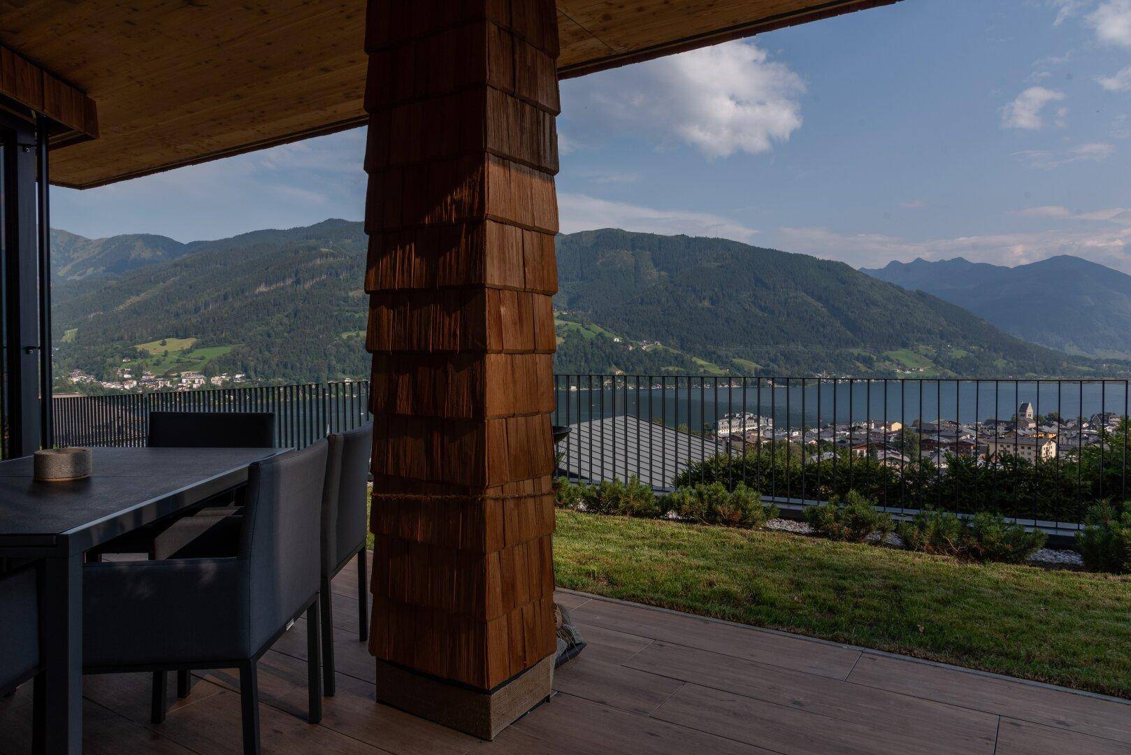 Geräumige Terrasse mit Esstisch und Stühlen, die einen atemberaubenden Blick auf den See und die umliegenden Berge bietet.