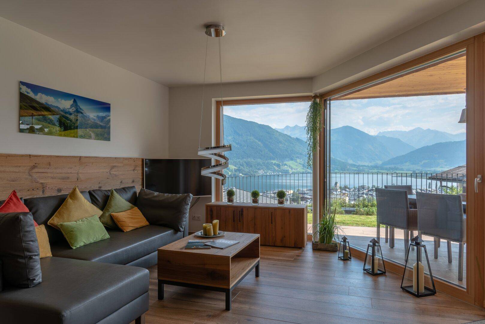 Helles Wohnzimmer mit gemütlichem Sofa, Holztisch und großen Fenstern mit Seeblick und Bergsicht.