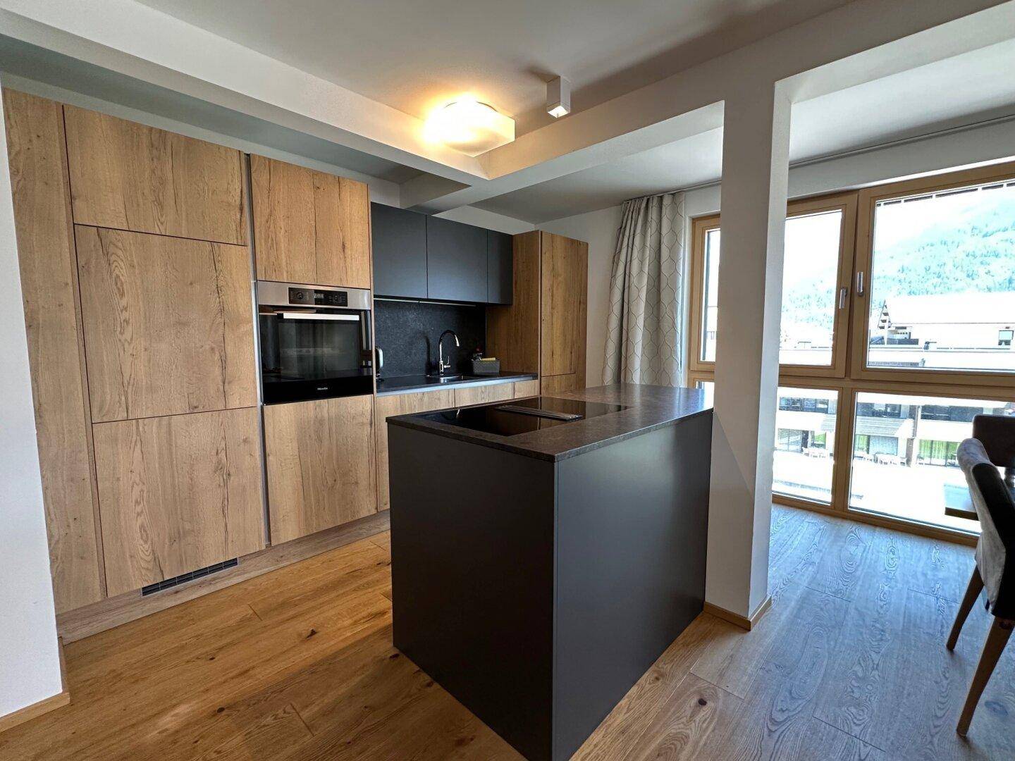 Moderne Einbauküche mit Holzfronten, dunkler Arbeitsplatte und Kücheninsel.