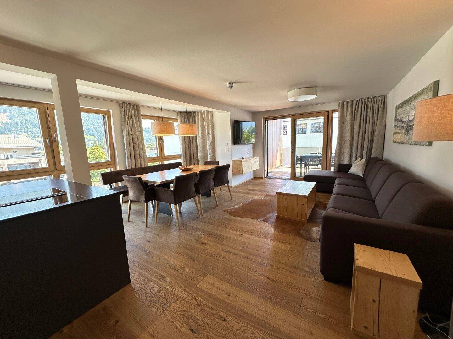 Heller offener Wohn- und Essbereich mit Holzboden und Zugang zum Balkon.