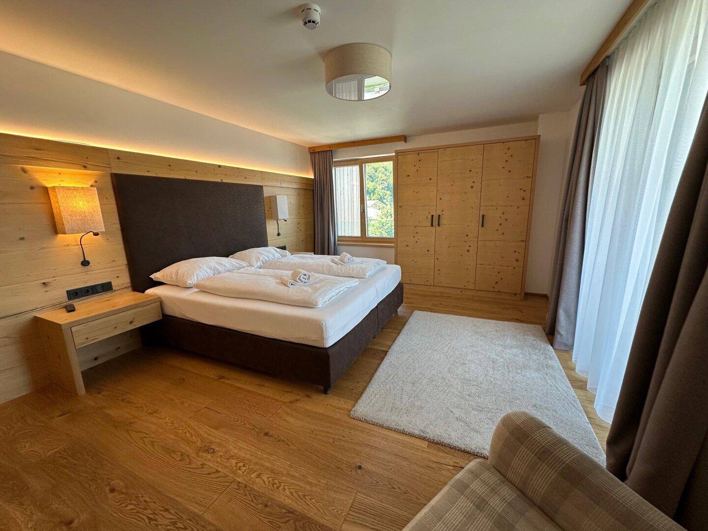 Gemütliches Schlafzimmer mit Holzboden, Doppelbett und Einbauschränken im alpinen Stil.