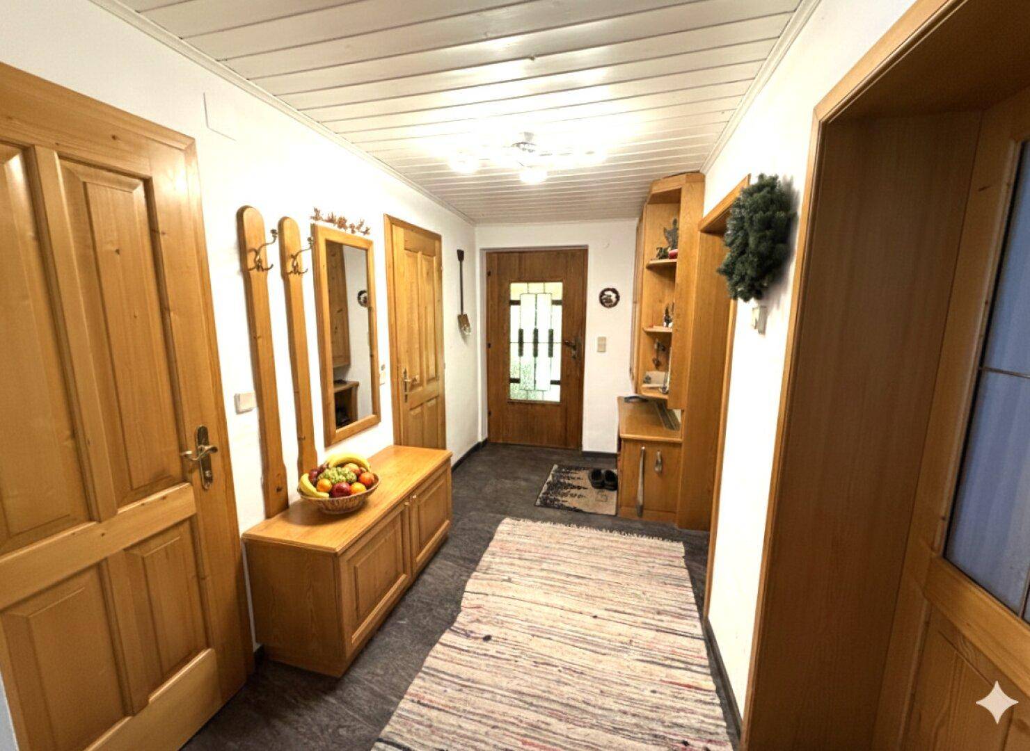 Heller Flur mit Holzmöbeln, Garderobe und traditioneller Eingangstür.