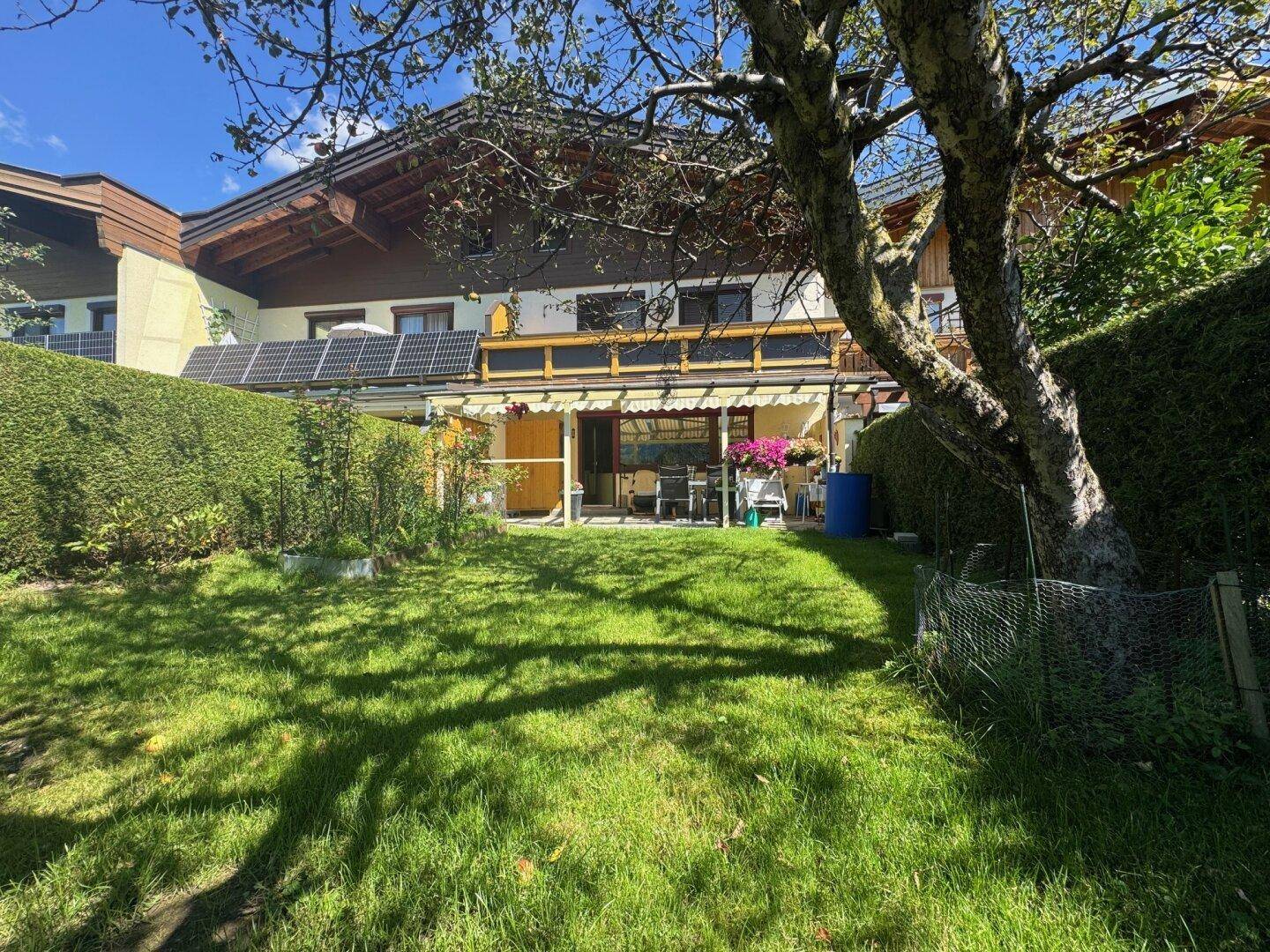Gepflegter Gartenbereich mit Rasenfläche und einer überdachten Terrasse am Haus.