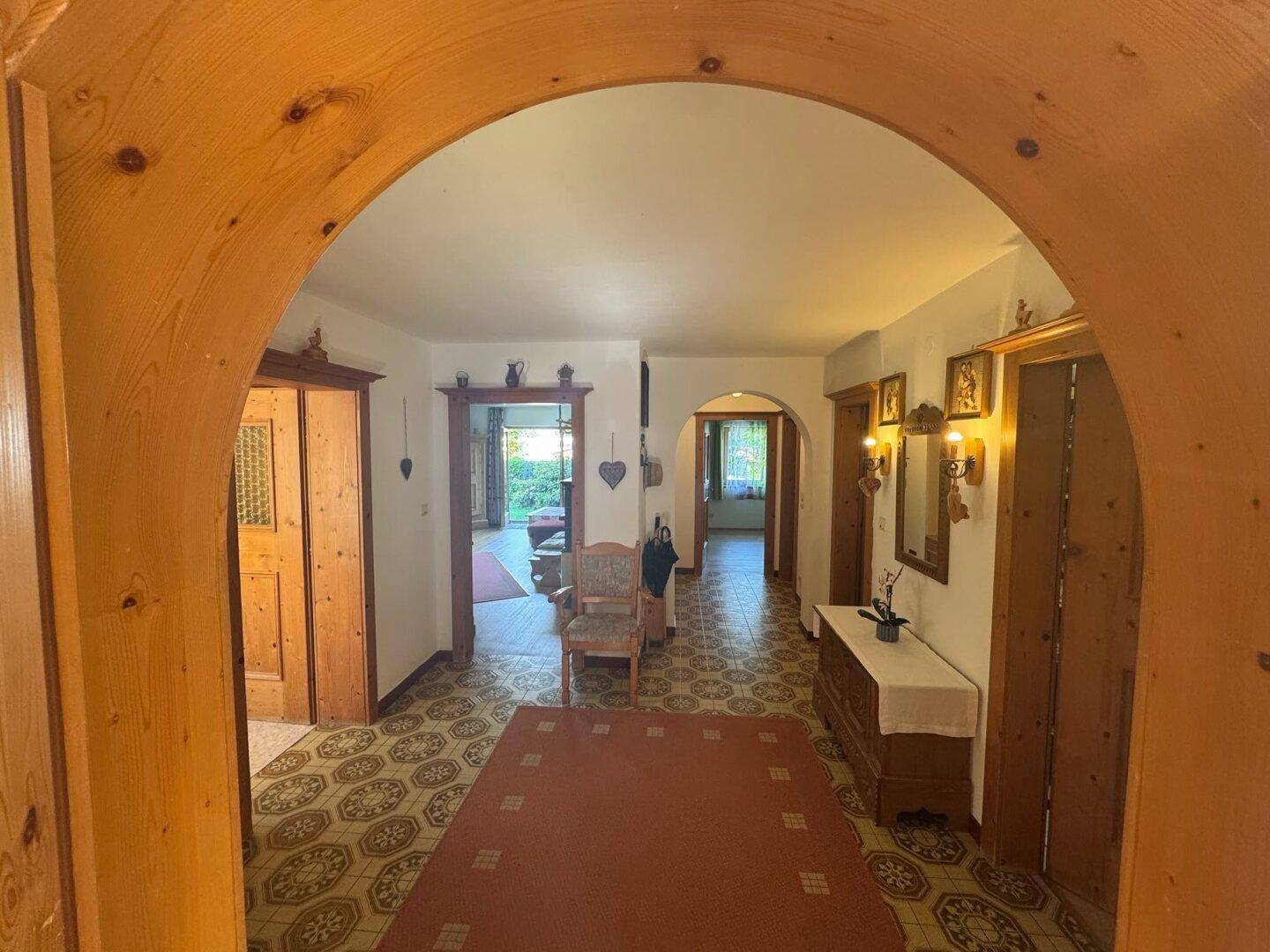 Gemütlicher Flur im Landhausstil mit Holzbögen, traditionellen Fliesen und rustikalen Möbeln.