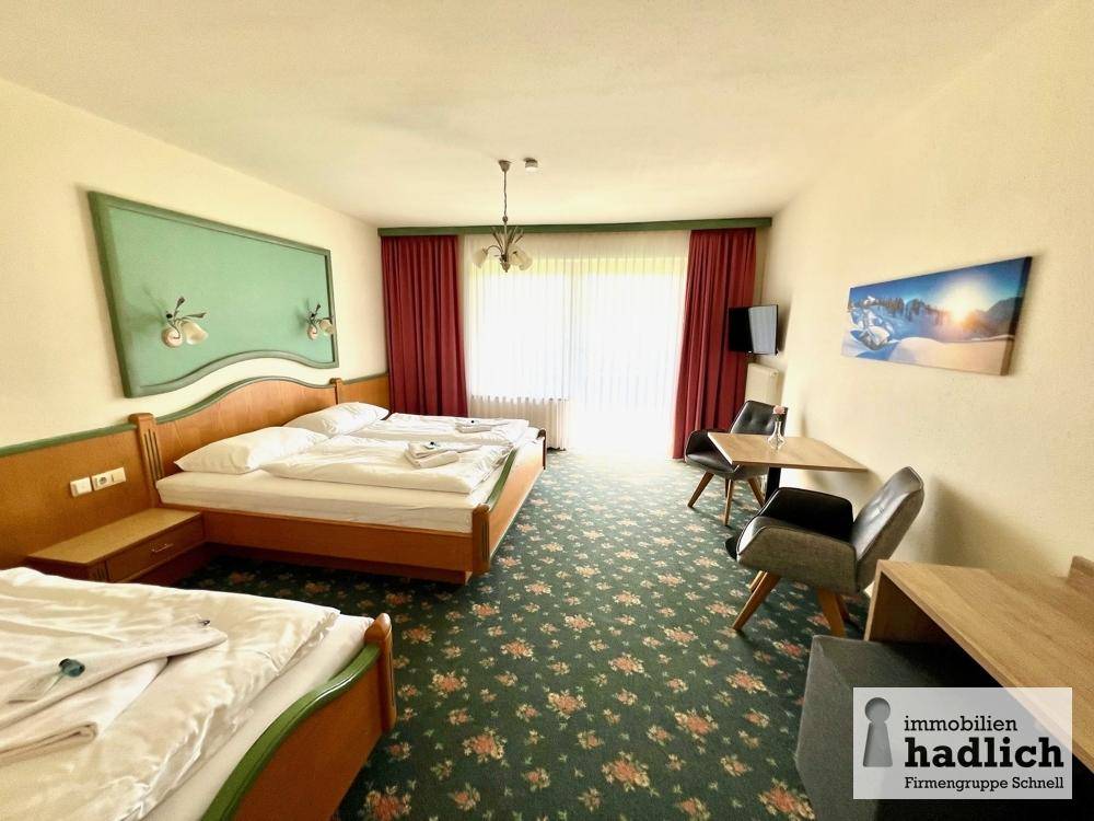 Gemütliches Schlafzimmer mit mehreren Betten, Teppichboden und Zugang zu einem Balkon oder einer Terrasse, ideal für Gäste.