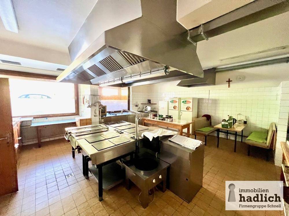 Professionelle Großküche mit Edelstahloberflächen, großen Dunstabzugshauben und funktionaler Ausstattung für den Gastronomiebetrieb.