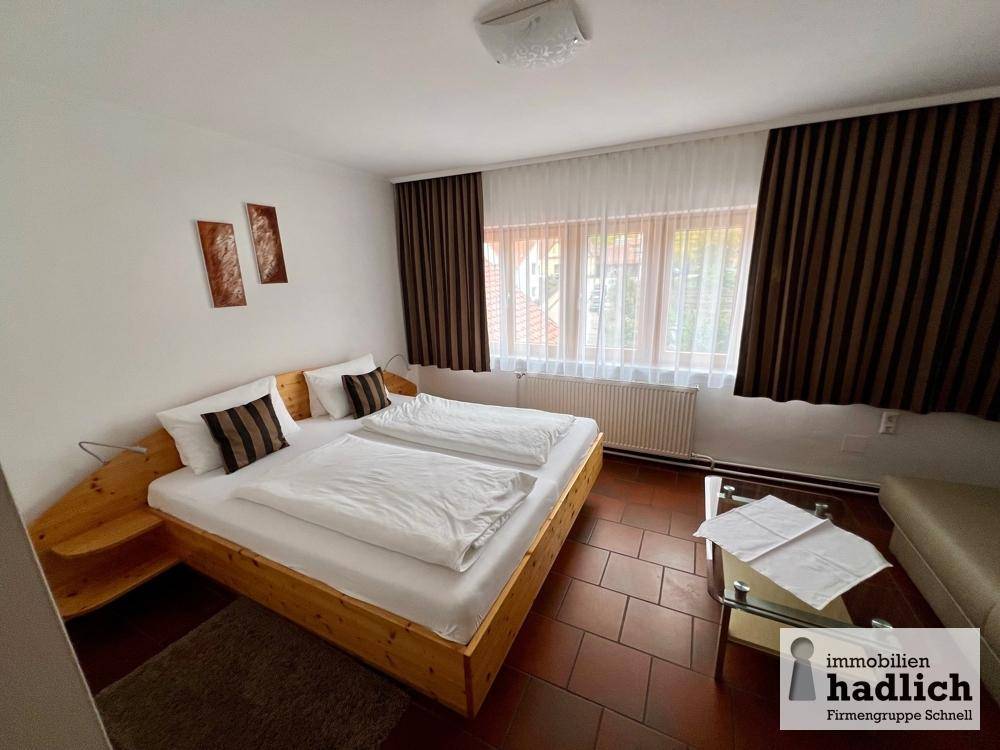 Gemütliches Schlafzimmer mit Doppelbett, braunen Vorhängen und gefliestem Boden.
