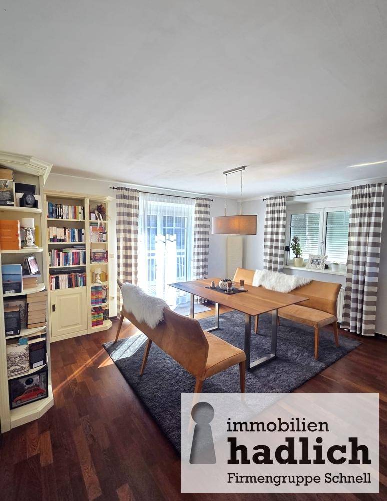 Heller Essbereich mit Holztisch, Sitzbänken und großem Bücherregal.