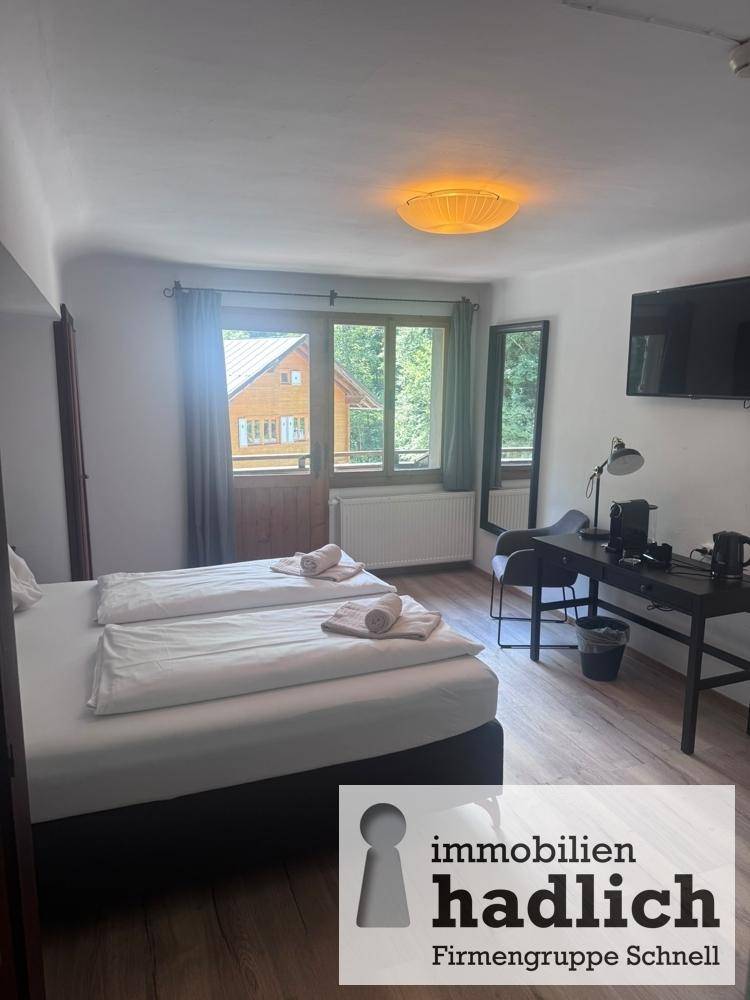 Schlafzimmer mit Doppelbett, Schreibtisch und Fenster mit Blick ins Grüne.