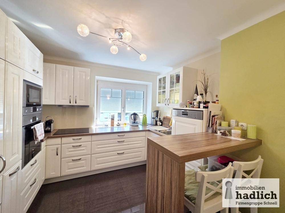 Helle Einbauküche mit weißen Schränken, integrierten Geräten und Frühstücksbar.