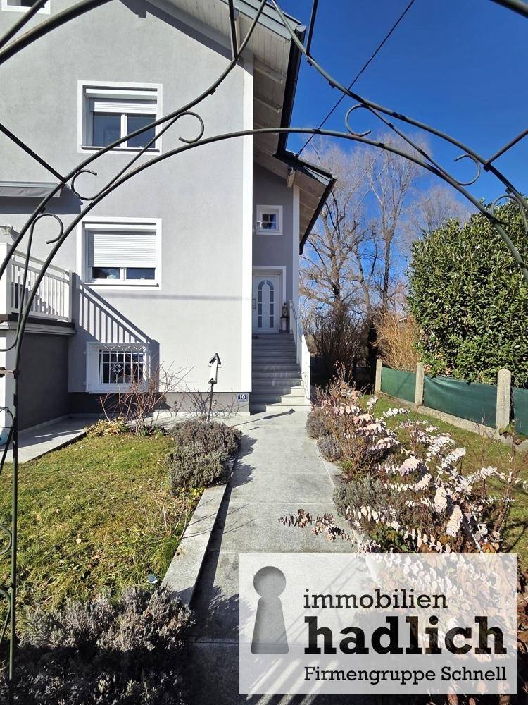 Eingangsbereich des Hauses mit gepflegtem Vorgarten und dekorativem Torbogen.