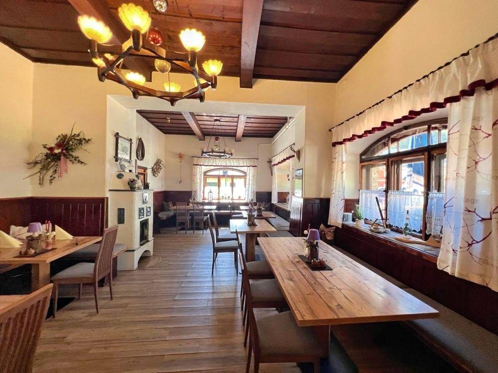 Geräumiger Speisesaal mit vielen Holztischen und Bänken, ideal für größere Gruppen, unter einer Holzbalkendecke.