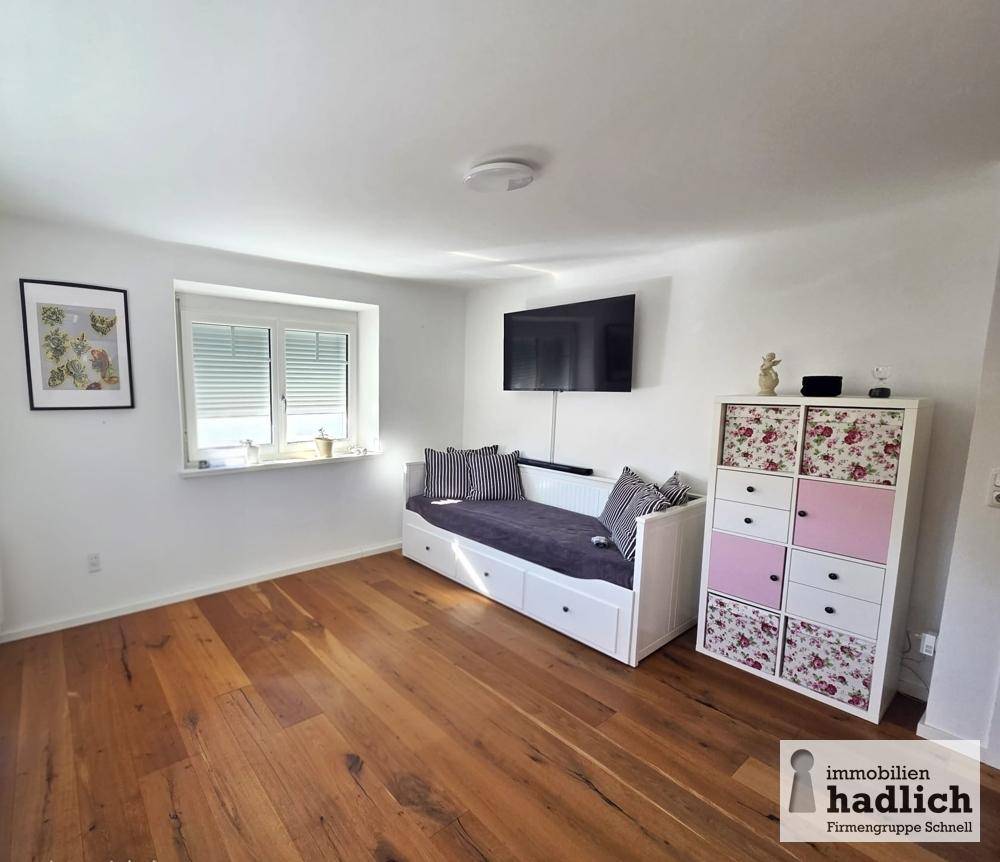 Helles Zimmer mit Holzboden, Tagesbett und praktischem Stauraum.