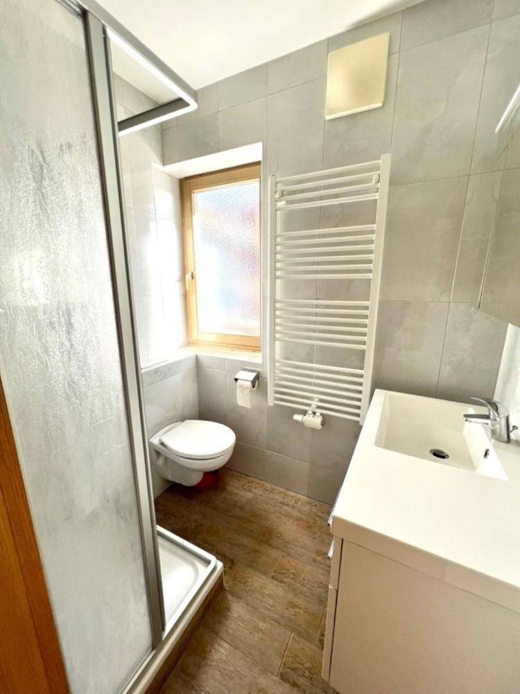 Modernes Badezimmer mit Duschkabine, WC, Waschbecken und einem Fenster für Tageslicht.