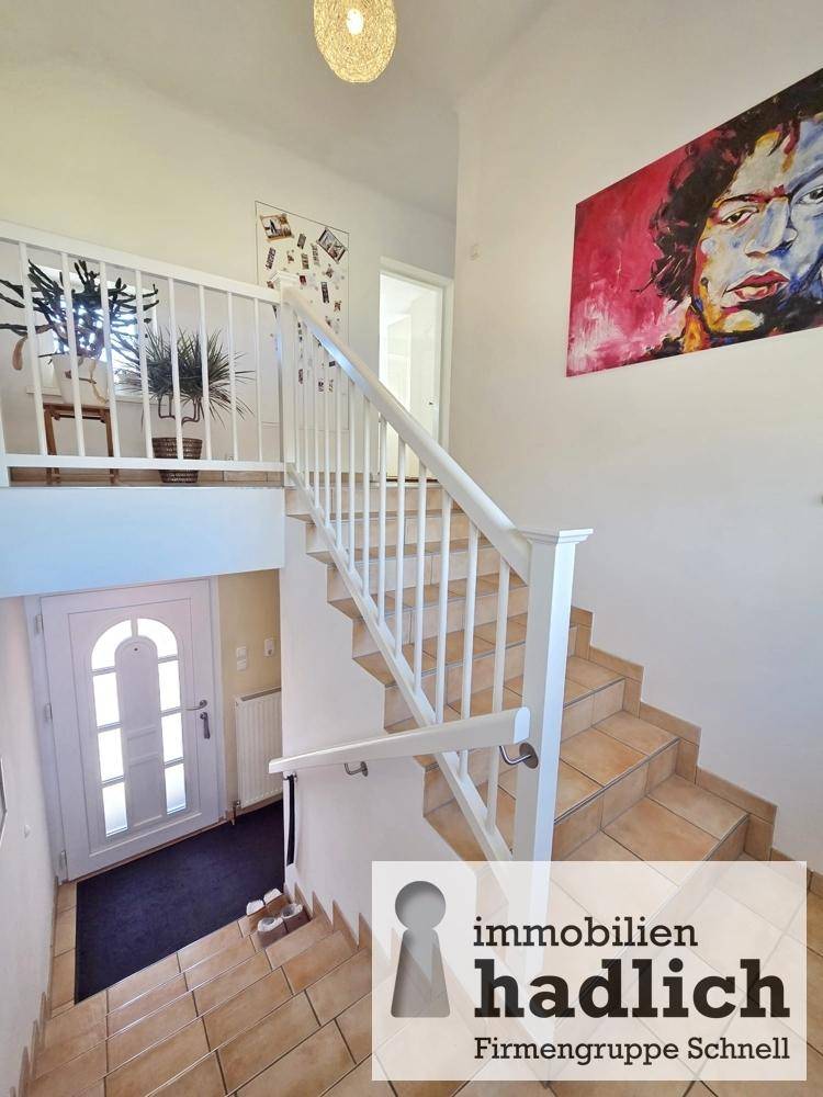 Heller Eingangsbereich mit gefliester Treppe und Zugang zu den oberen Etagen.