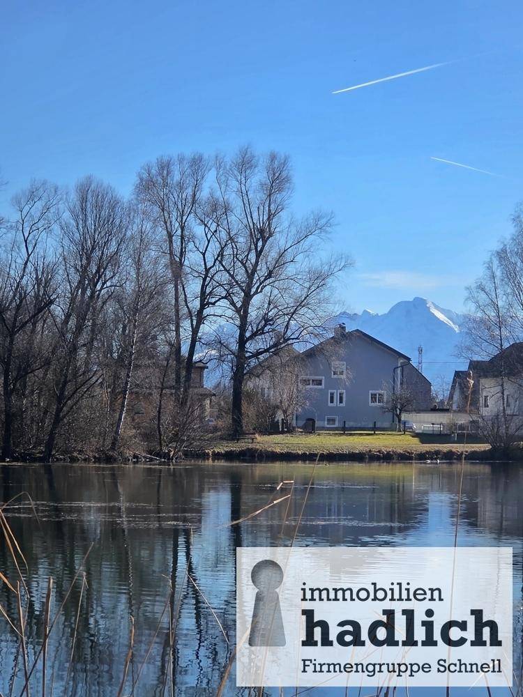 Haus am Seeufer mit beeindruckendem Bergblick unter blauem Himmel.