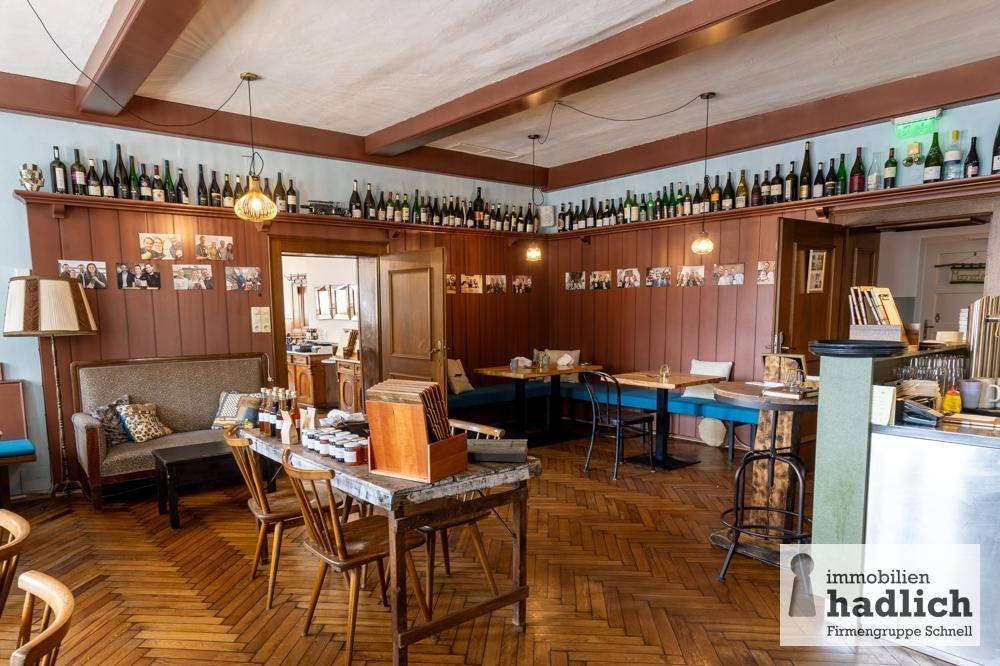 Rustikaler Loungebereich mit Holzvertäfelung, gemütlichen Sitzgelegenheiten und einer Sammlung von Weinflaschen.