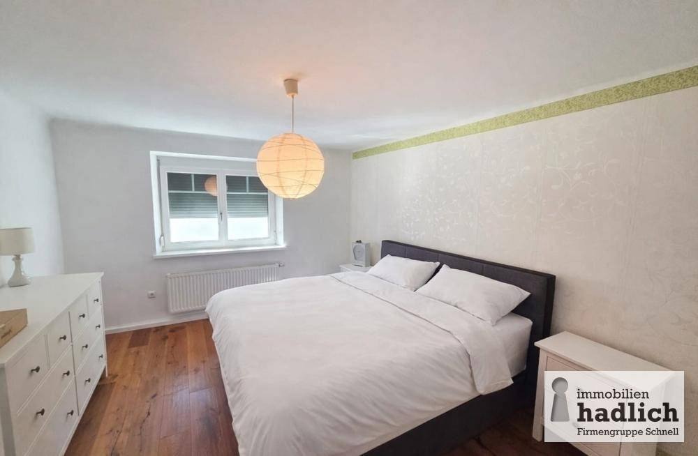 Gemütliches Schlafzimmer mit Doppelbett, Holzboden und Fenster mit Rollladen.