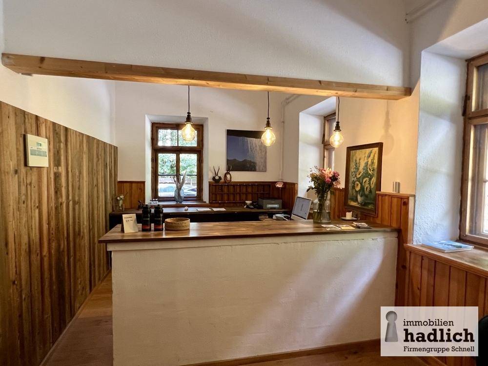 Empfangsbereich mit Holztheke, Holzvertäfelung an den Wänden und sichtbaren Holzbalken an der Decke.