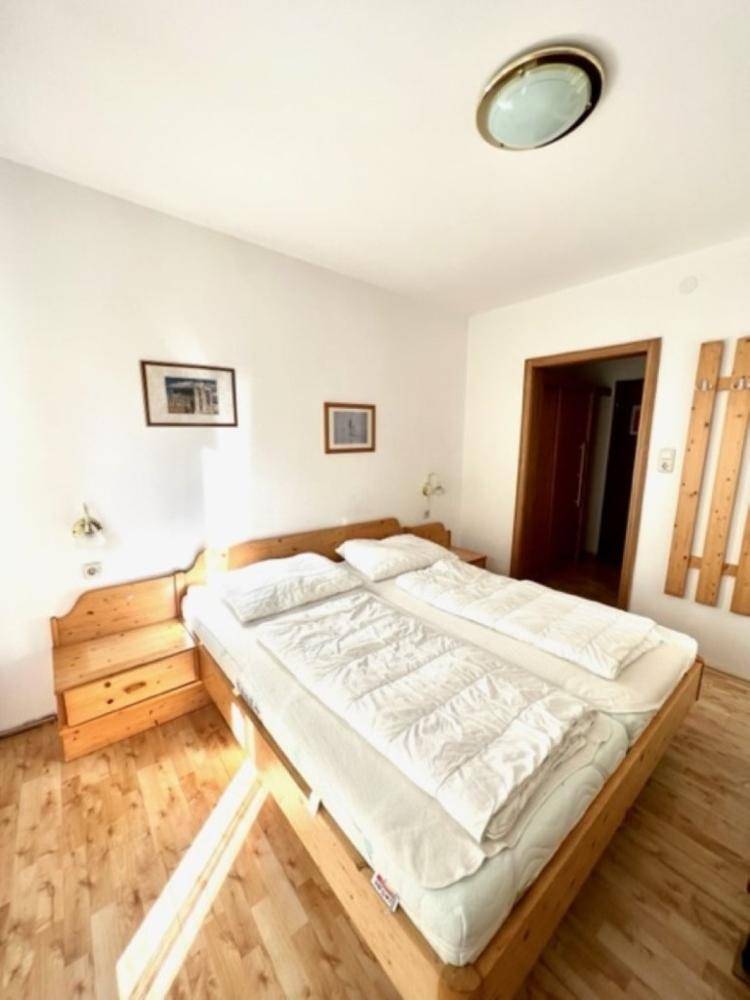 Helles Schlafzimmer mit Doppelbett, Nachttischen aus Holz und einem warmen Holzboden.