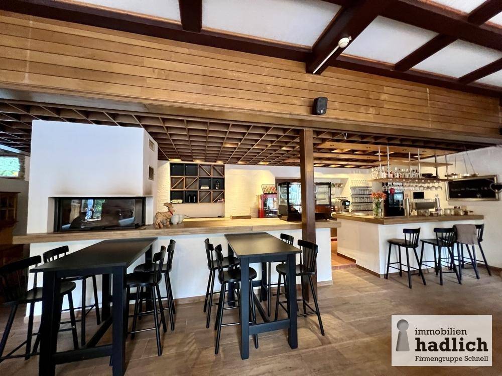 Moderne Bar und Loungebereich mit Kamin, hohen Tischen und einer gut ausgestatteten Theke.