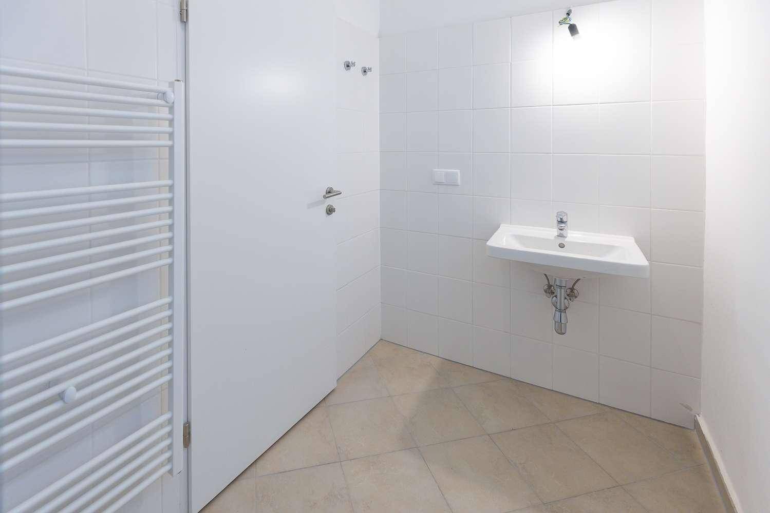 Helles Badezimmer mit Waschbecken, weißen Fliesen und einem praktischen Handtuchheizkörper.