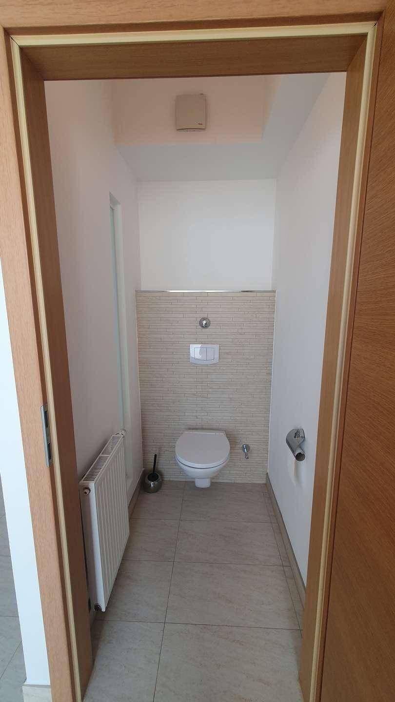 Separates WC mit Wand-WC, Heizkörper und Fliesenboden, praktisch und funktional gestaltet.