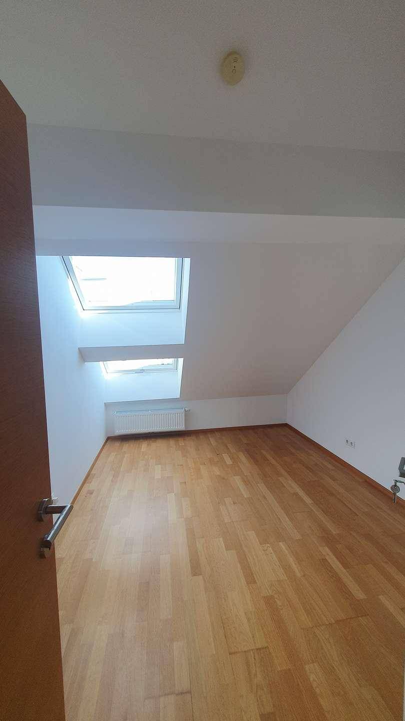 Schlafzimmer im Dachgeschoss mit Holzboden, Dachfenstern und Heizkörper, ideal für ein gemütliches Ambiente.