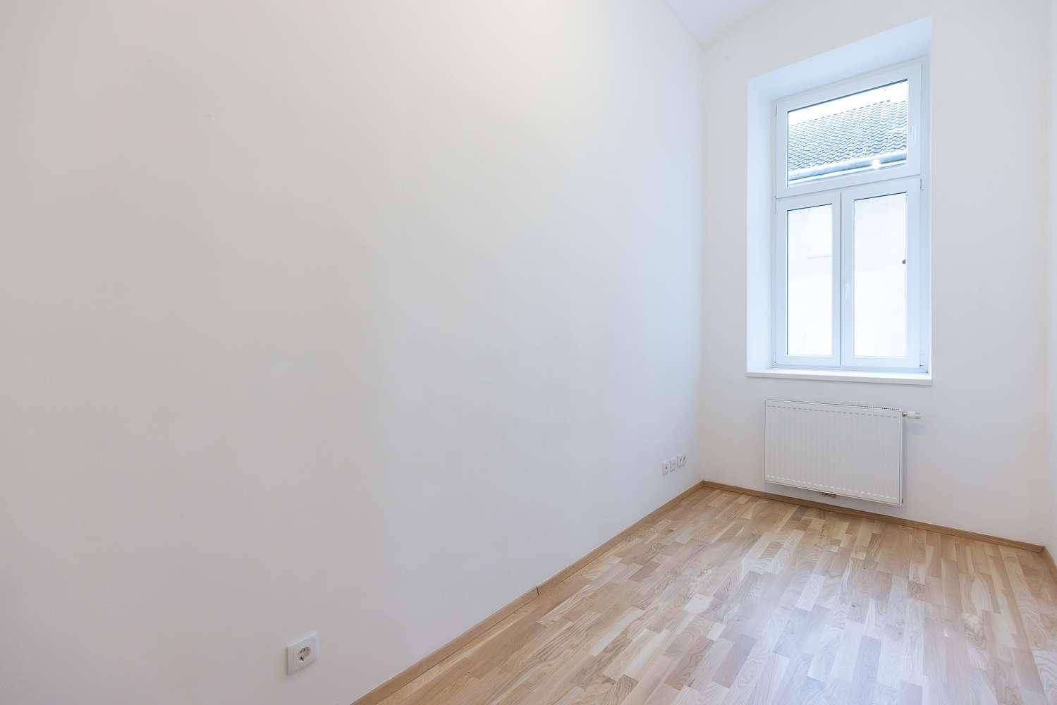 Helles Zimmer mit Parkettboden, weißen Wänden und einem Fenster, das für gute Belüftung sorgt.