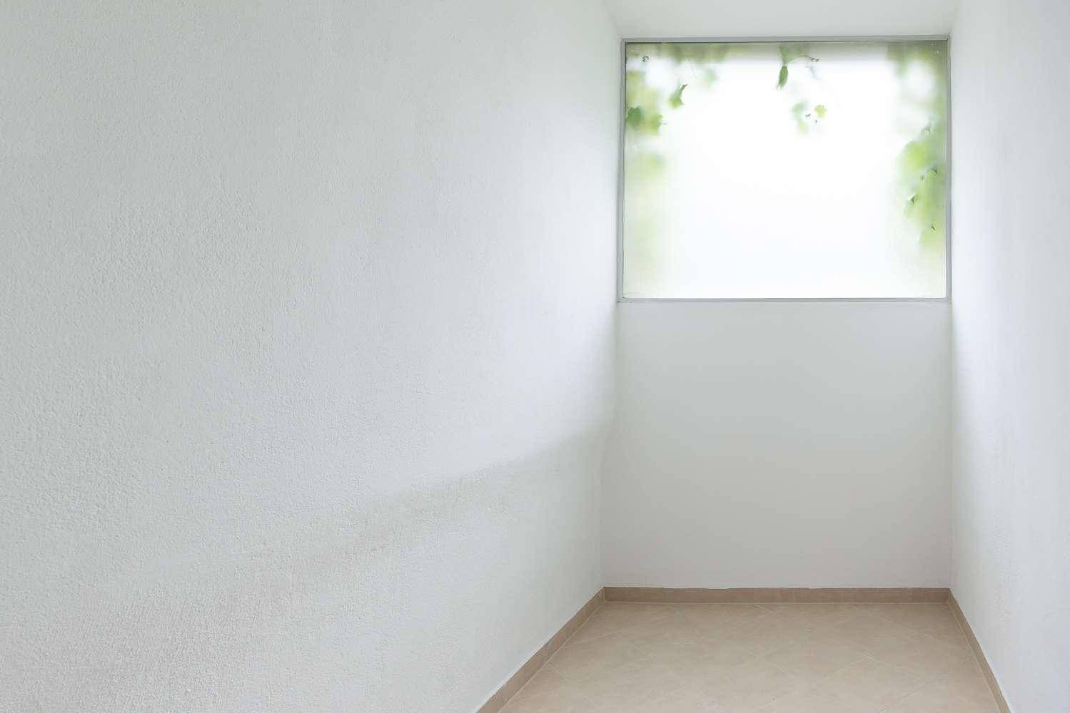 Schmaler Raum mit Fliesenboden und einem hohen, blickdichten Fenster für Privatsphäre.