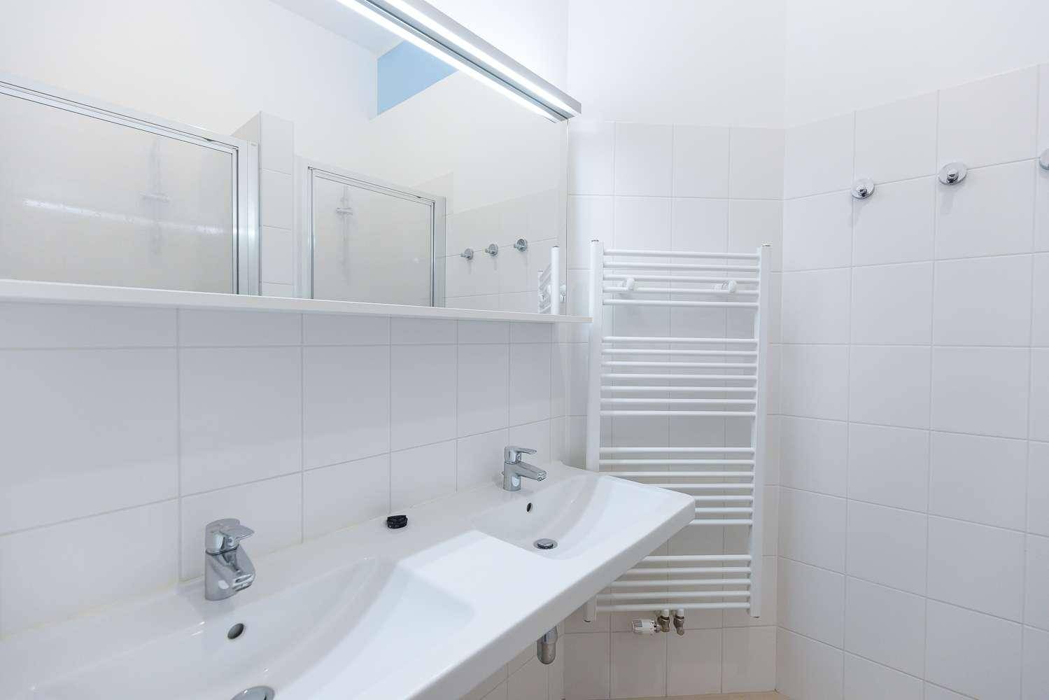 Modernes Badezimmer mit Doppelwaschbecken, großem Spiegel und praktischem Handtuchheizkörper.