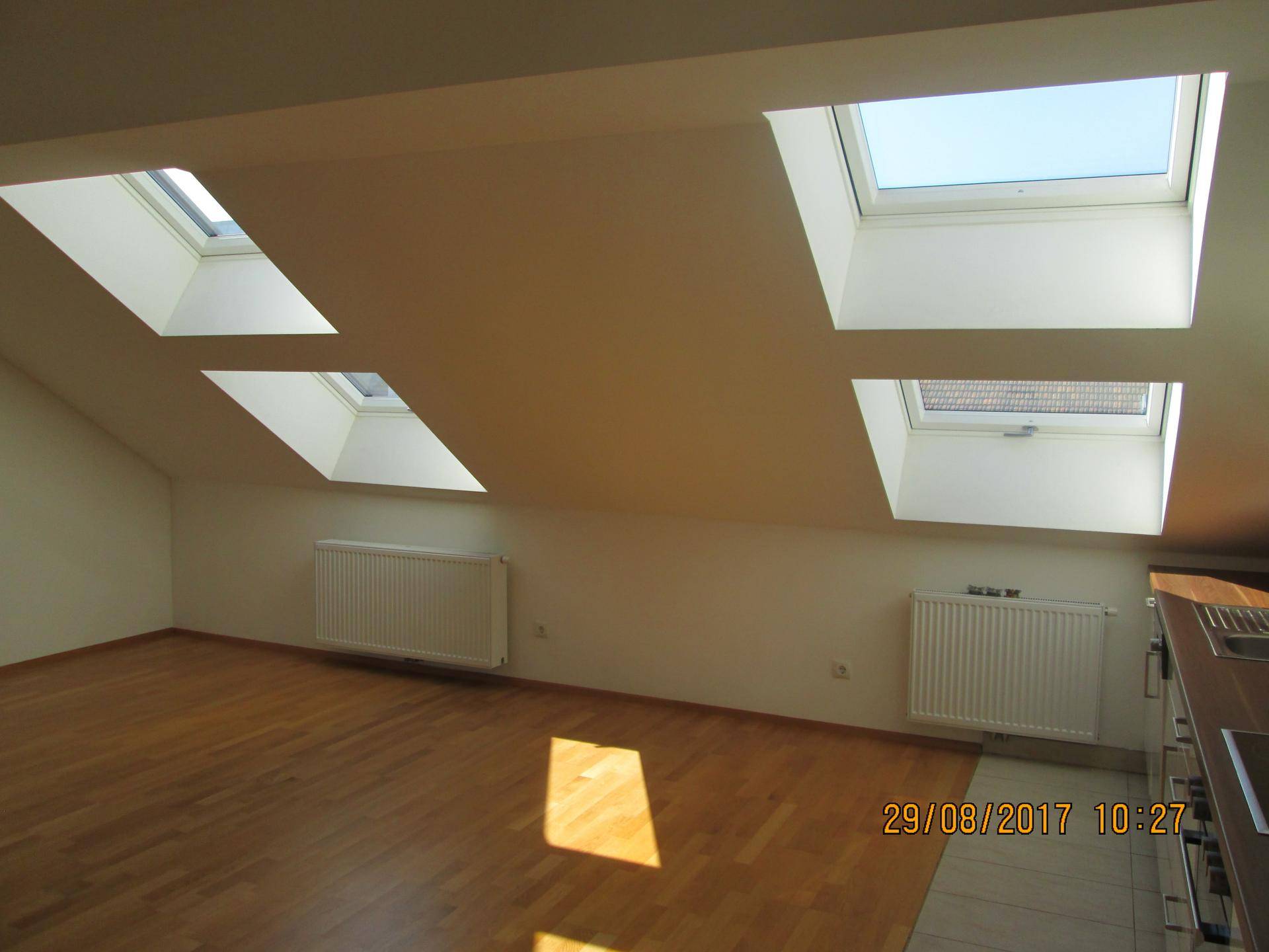 Heller Wohnbereich mit Holzparkett, Dachschrägen und mehreren Dachfenstern für viel Licht.