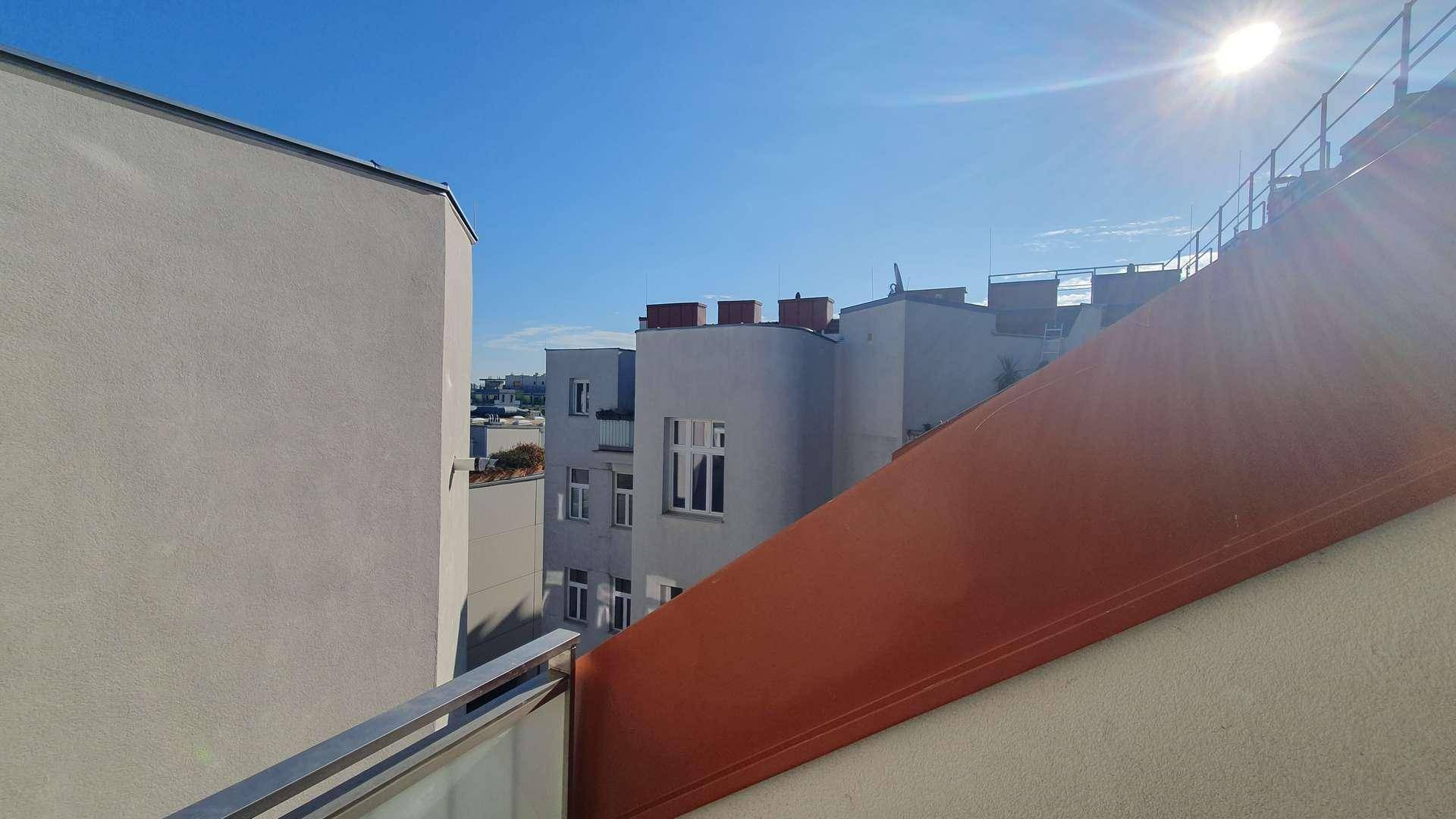 Sonniger Ausblick über die Dächer der Stadt mit umliegenden Gebäuden und klarem Himmel.