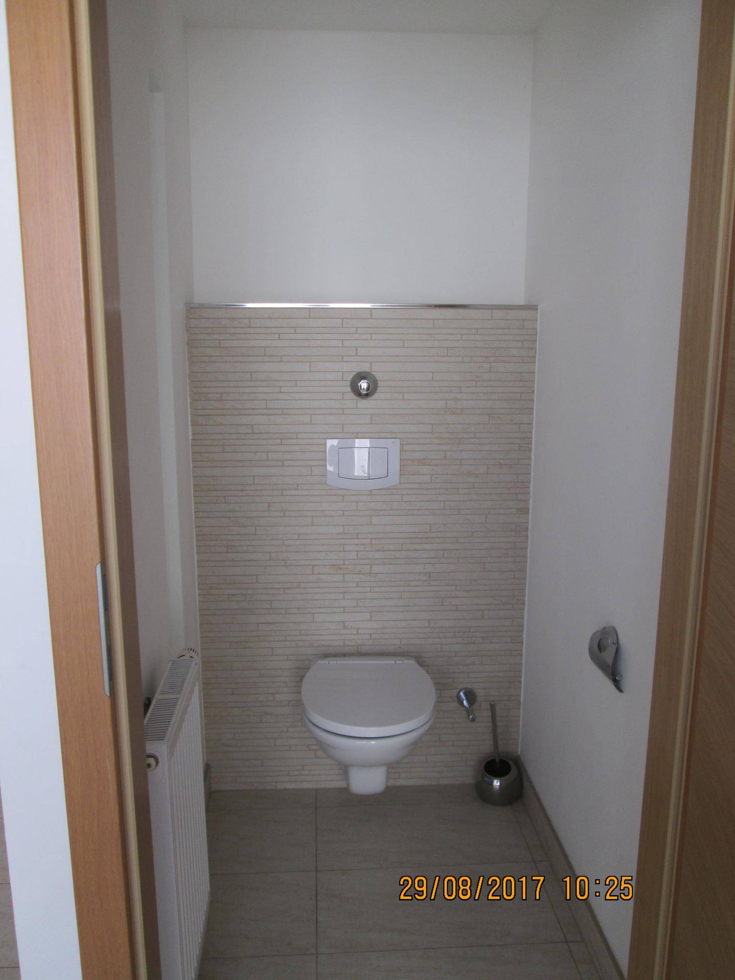 Modernes Gäste-WC mit wandhängender Toilette und beigefarbenen Fliesen an der Wand.