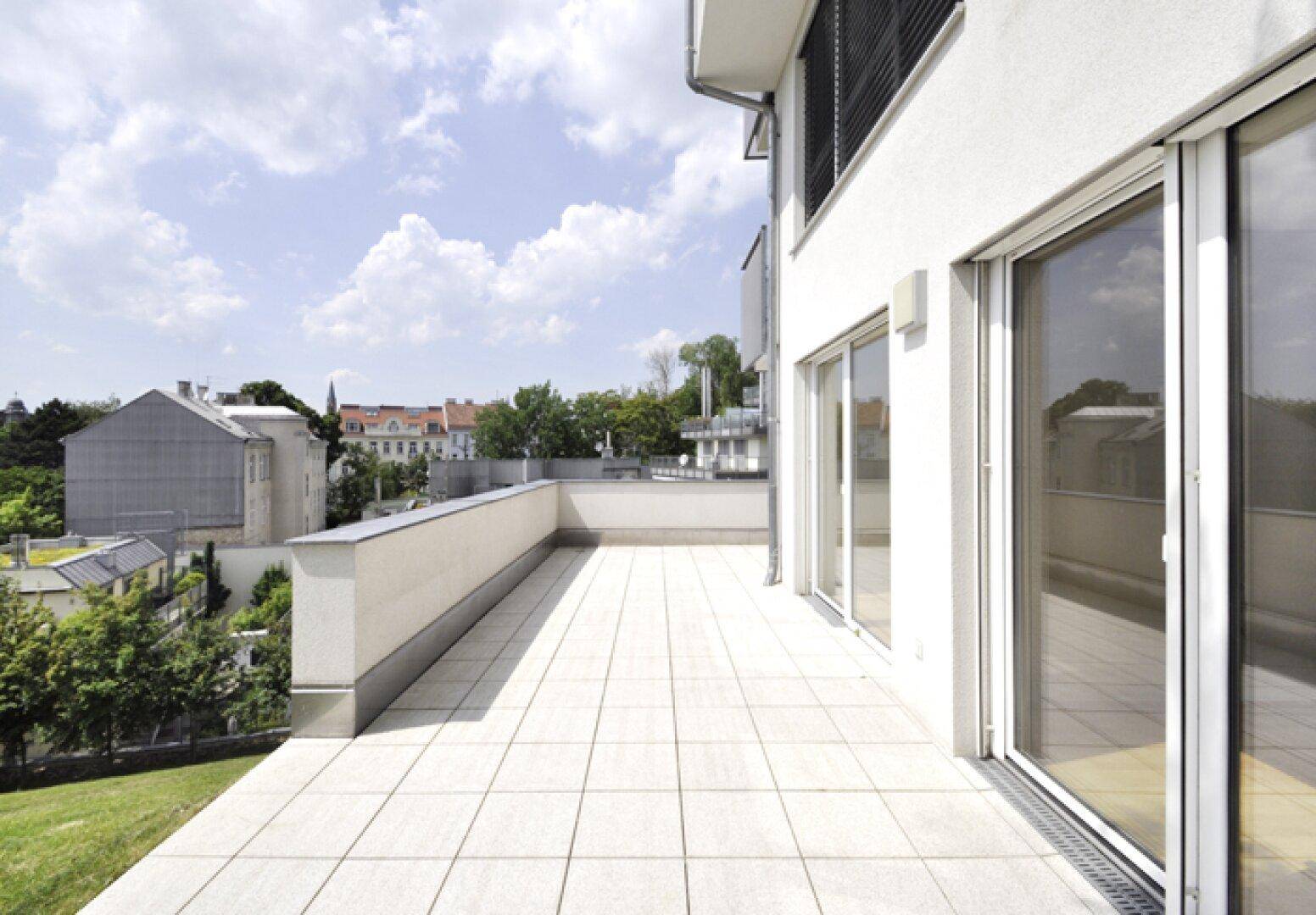 Helle Terrasse mit weitem Blick über die Stadt und die umliegenden Gebäude.