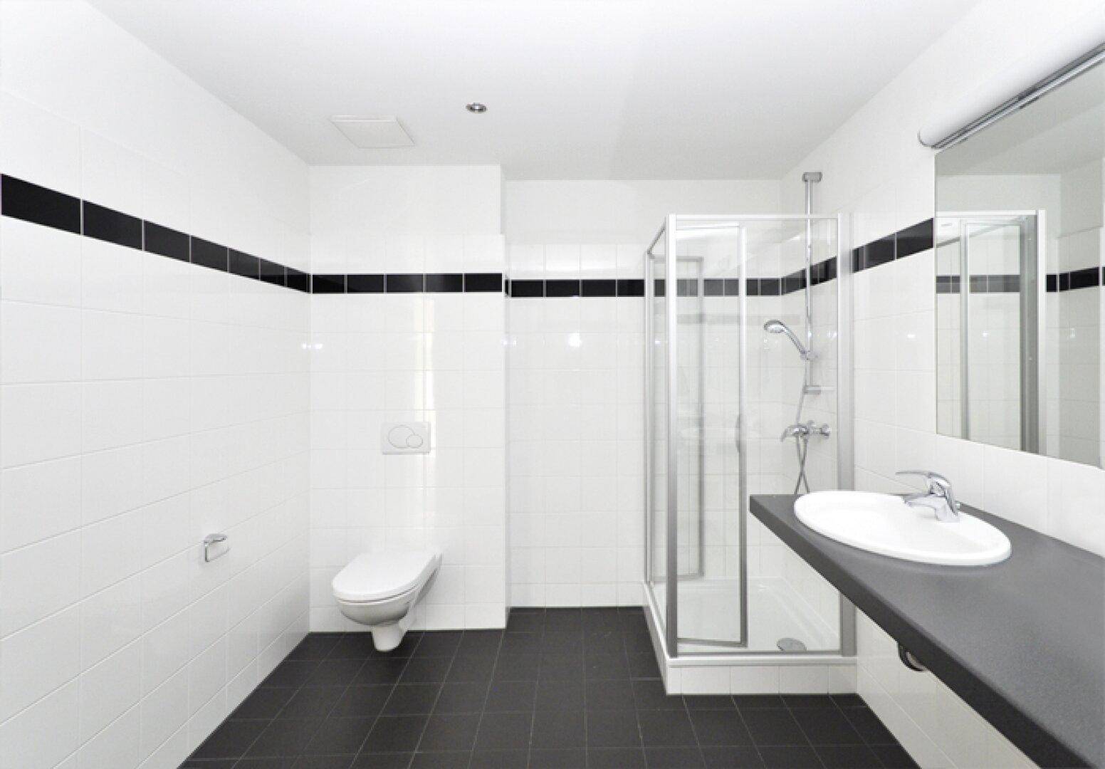 Funktionales Badezimmer mit Dusche, WC und Einzelwaschbecken in schwarz-weißem Design.
