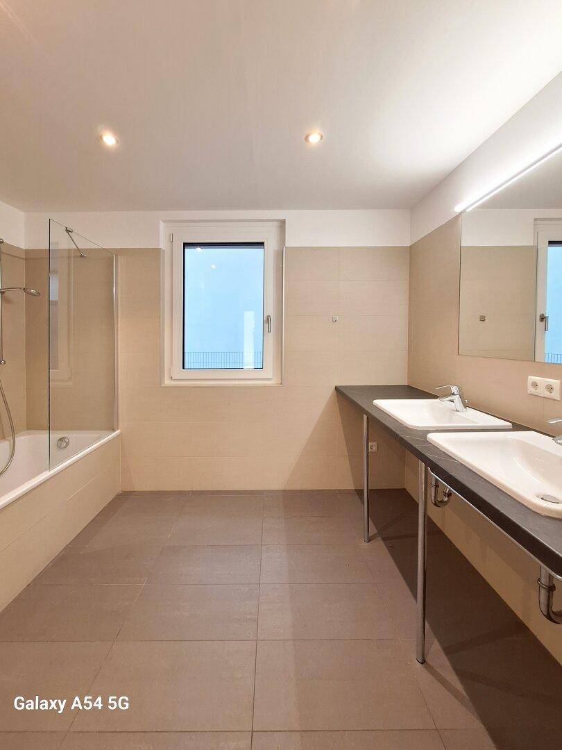 Modernes Badezimmer mit Doppelwaschbecken, Badewanne und Fenster.