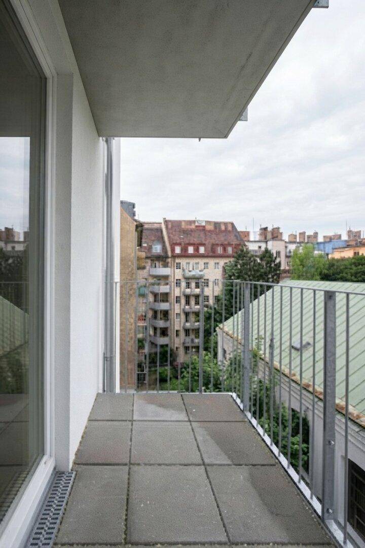 Kleiner Balkon mit Fliesenboden und Blick auf die umliegenden Gebäude der Stadt.