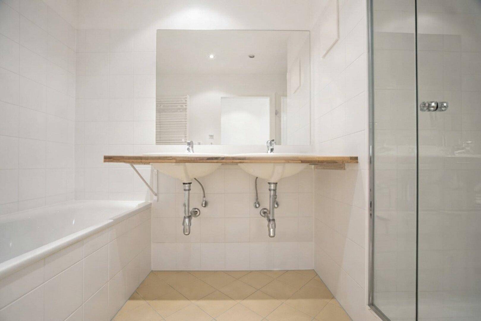 Modernes Badezimmer mit Doppelwaschbecken, Badewanne und separater Duschkabine.