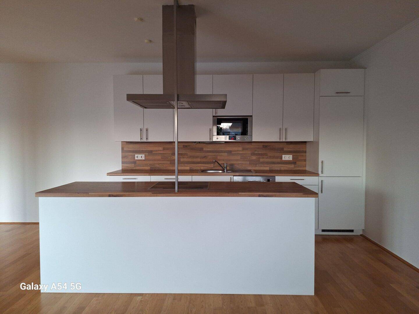 Moderne Küche mit weißer Einbauküche, Holz-Arbeitsplatten und zentraler Kochinsel.