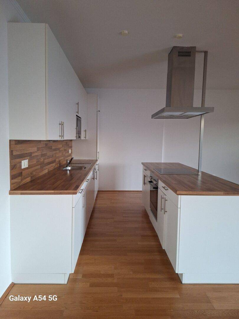 Helle Einbauküche mit Kochinsel, weißen Schränken und Holz-Arbeitsplatten in einem modernen Design.