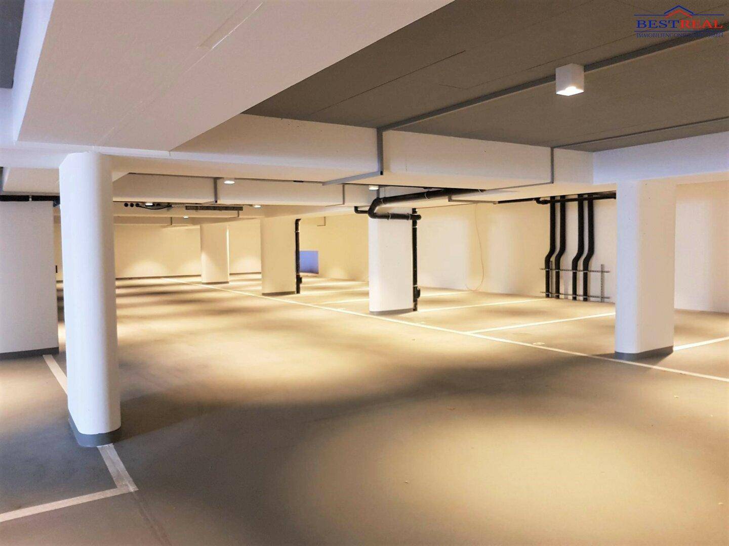 Saubere und geräumige Tiefgarage mit Betonboden und klar gekennzeichneten Parkplätzen.