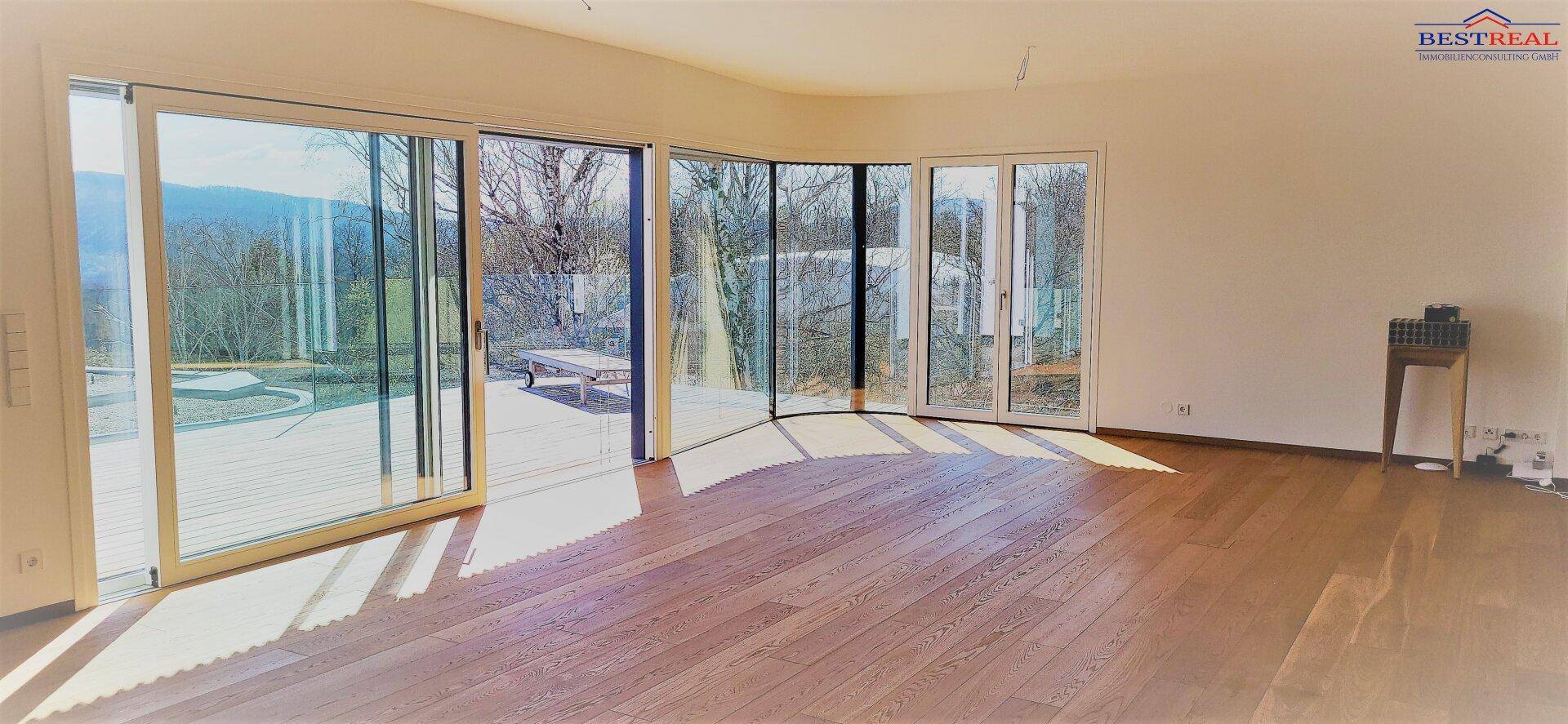 Heller Wohnbereich mit großen Schiebetüren und Zugang zu einer Terrasse mit Panoramablick.