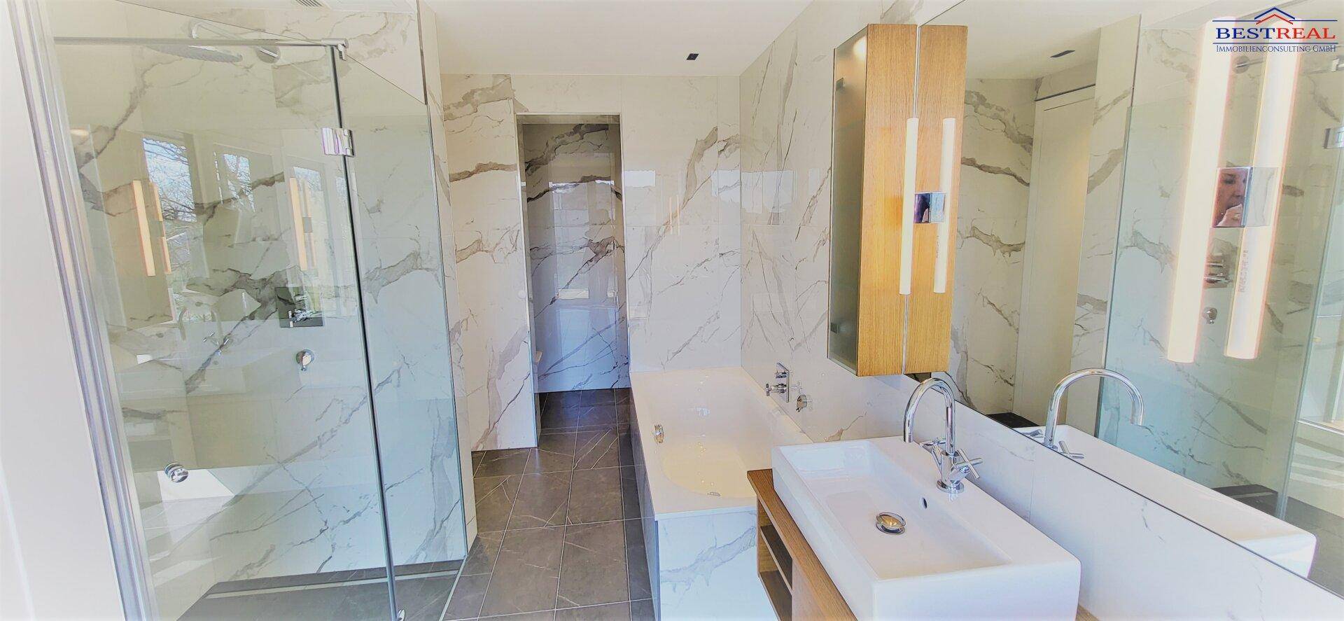 Elegantes Badezimmer mit Marmorfliesen, Einzelwaschbecken und großer begehbarer Dusche.