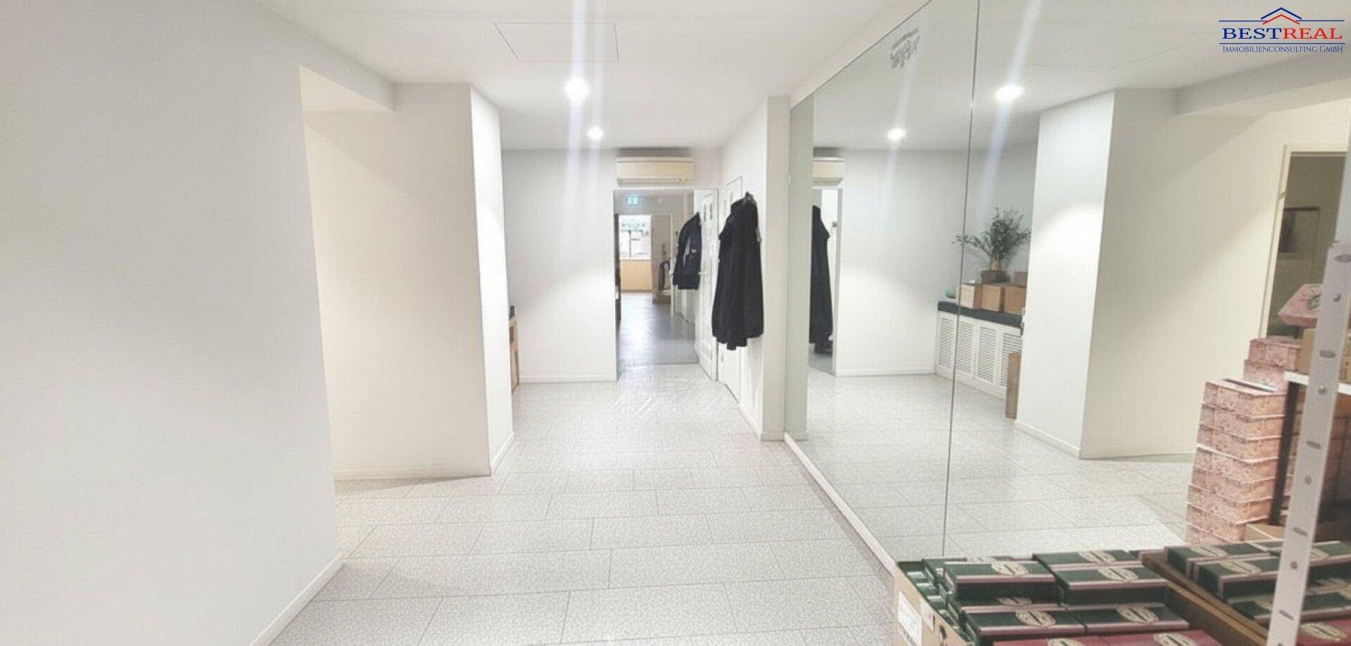 Heller Flur mit großen Spiegeln, Fliesenboden und Garderobe im Hintergrund.