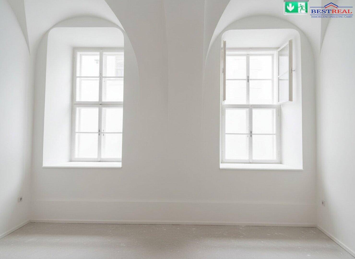 Ein leerer Raum mit hohen, gewölbten Fenstern und einem Gewölbe an der Decke, frisch renoviert.