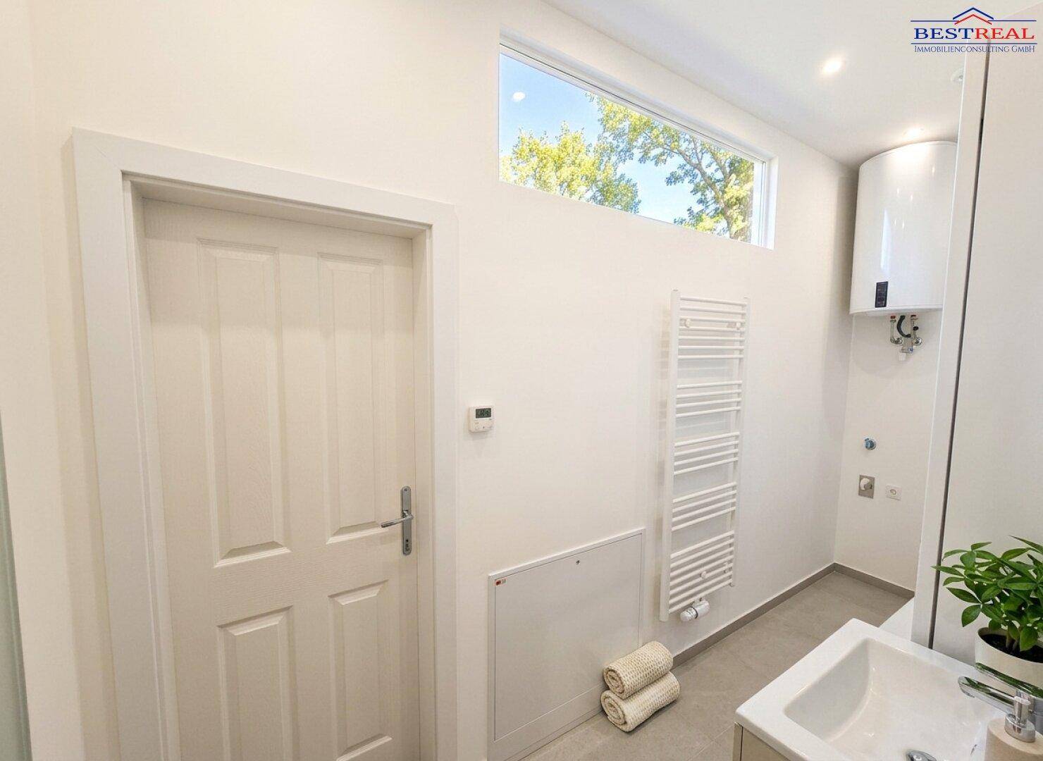 Modernes Badezimmer mit Waschbecken, beheiztem Handtuchhalter und Oberlichtfenster.