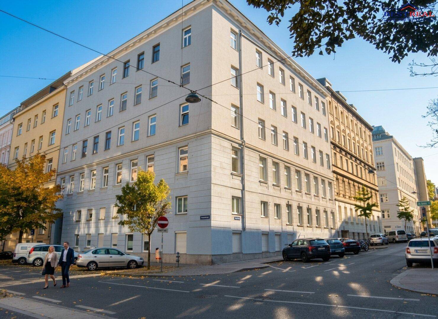 Eckgebäude in urbaner Umgebung mit klassischer Architektur und parkenden Autos auf der Straße.